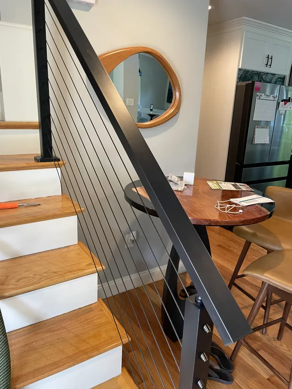 Black handrail and cable infill along an interior wood staircase