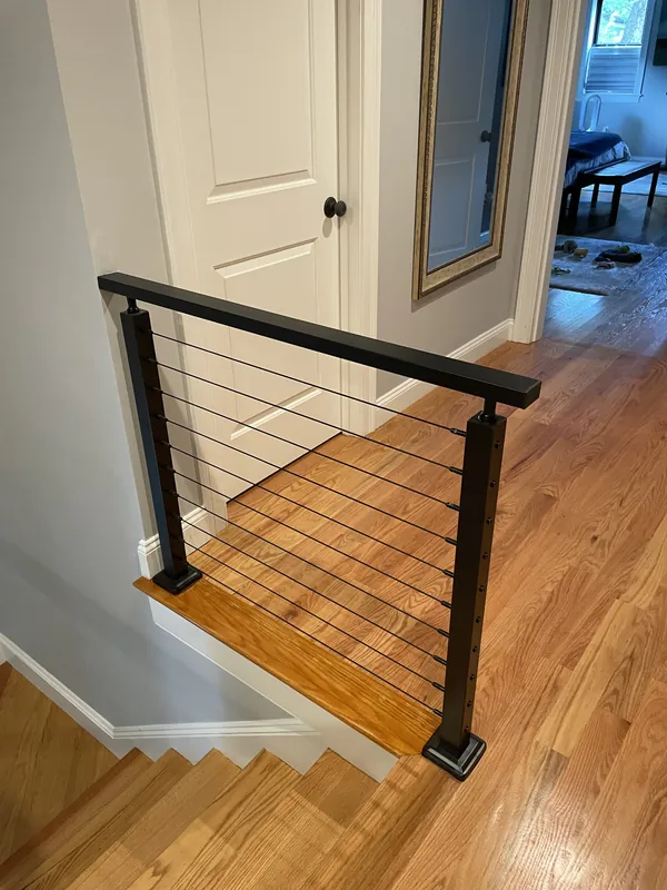 Black cable railing surrounding an upstairs stair opening