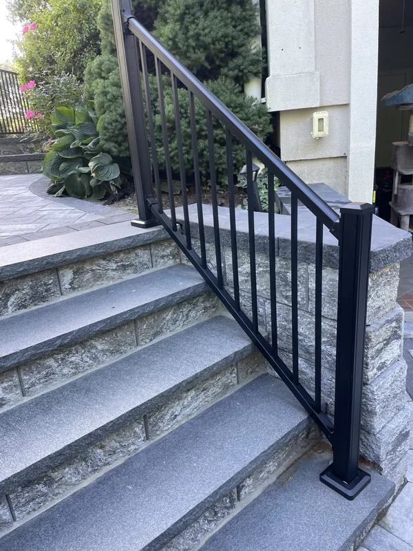 Black vertical-baluster railing along exterior stone steps
