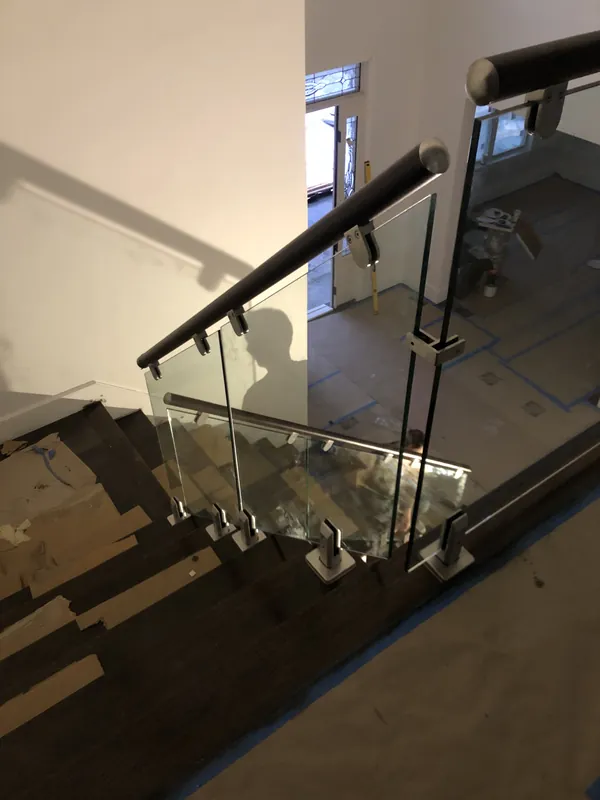 Glass stair railing with dark posts and a matching handrail