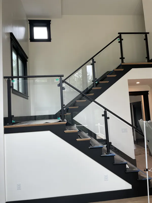 Glass panels with black posts and handrails on a modern interior staircase